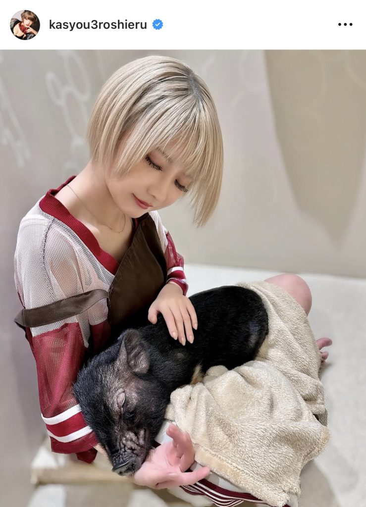 ミニブタを抱いて優しい表情を見せる