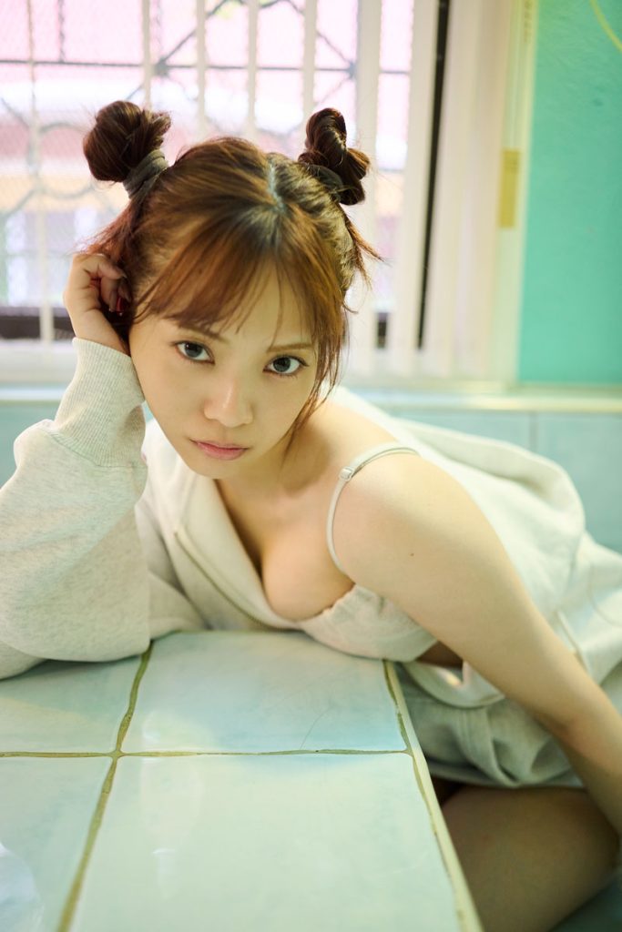 「宮田愛萌1st写真集『Lilas』」(幻冬舎)より、現地のおうちを借りて撮影したカット。パステルカラーのタイルにリラックスムードなスタイリング、おだんごヘアもかわいい1枚